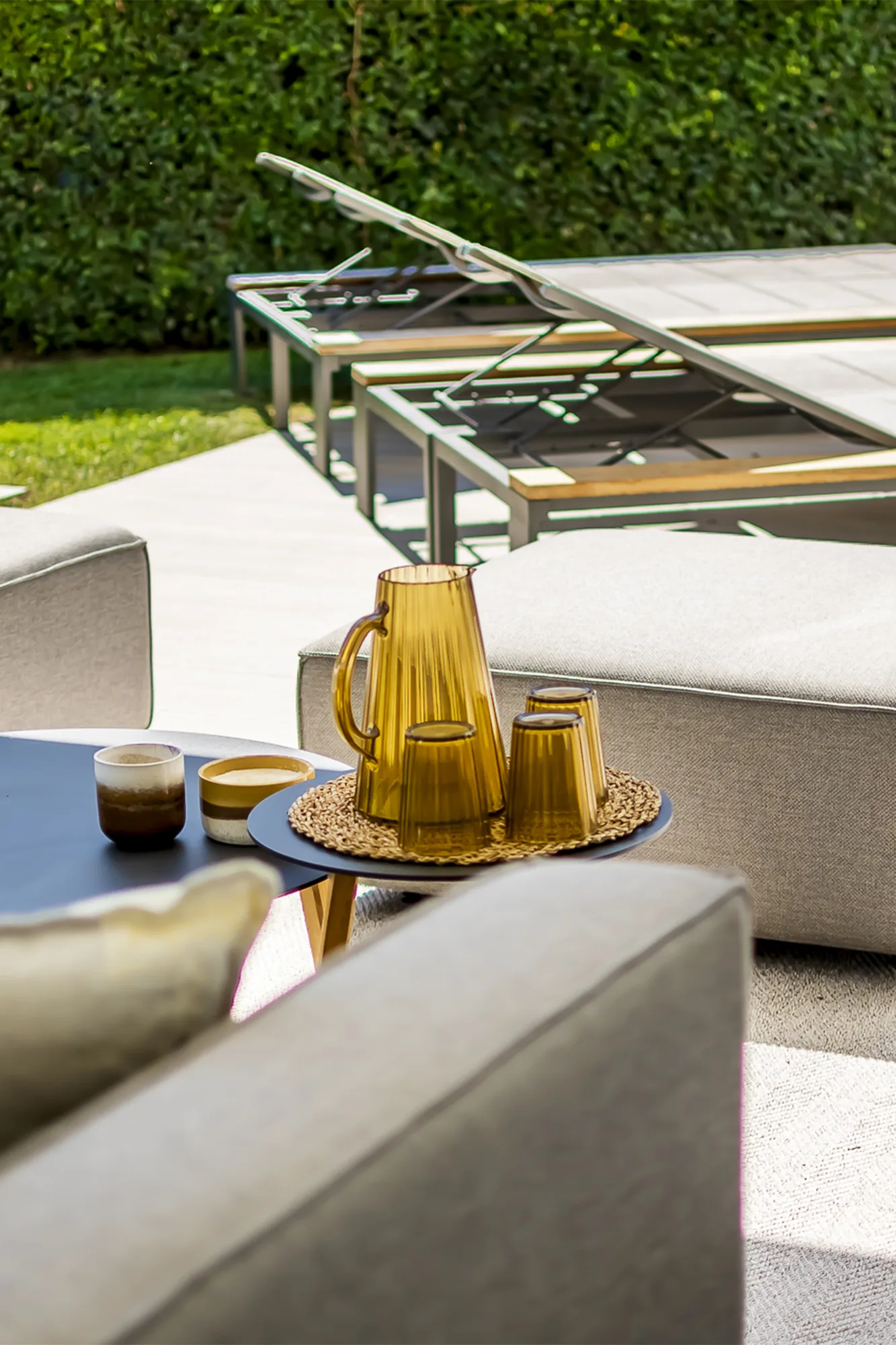 Terraço exterior com espreguiçadeiras, sebe alta e piscina.