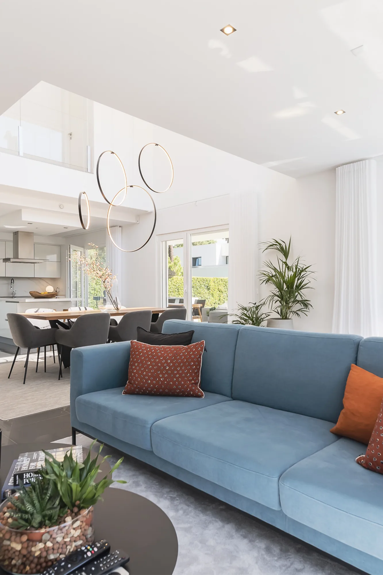 Sala aberta para a zona de refeições, com sofá azul e mesa ao fundo.