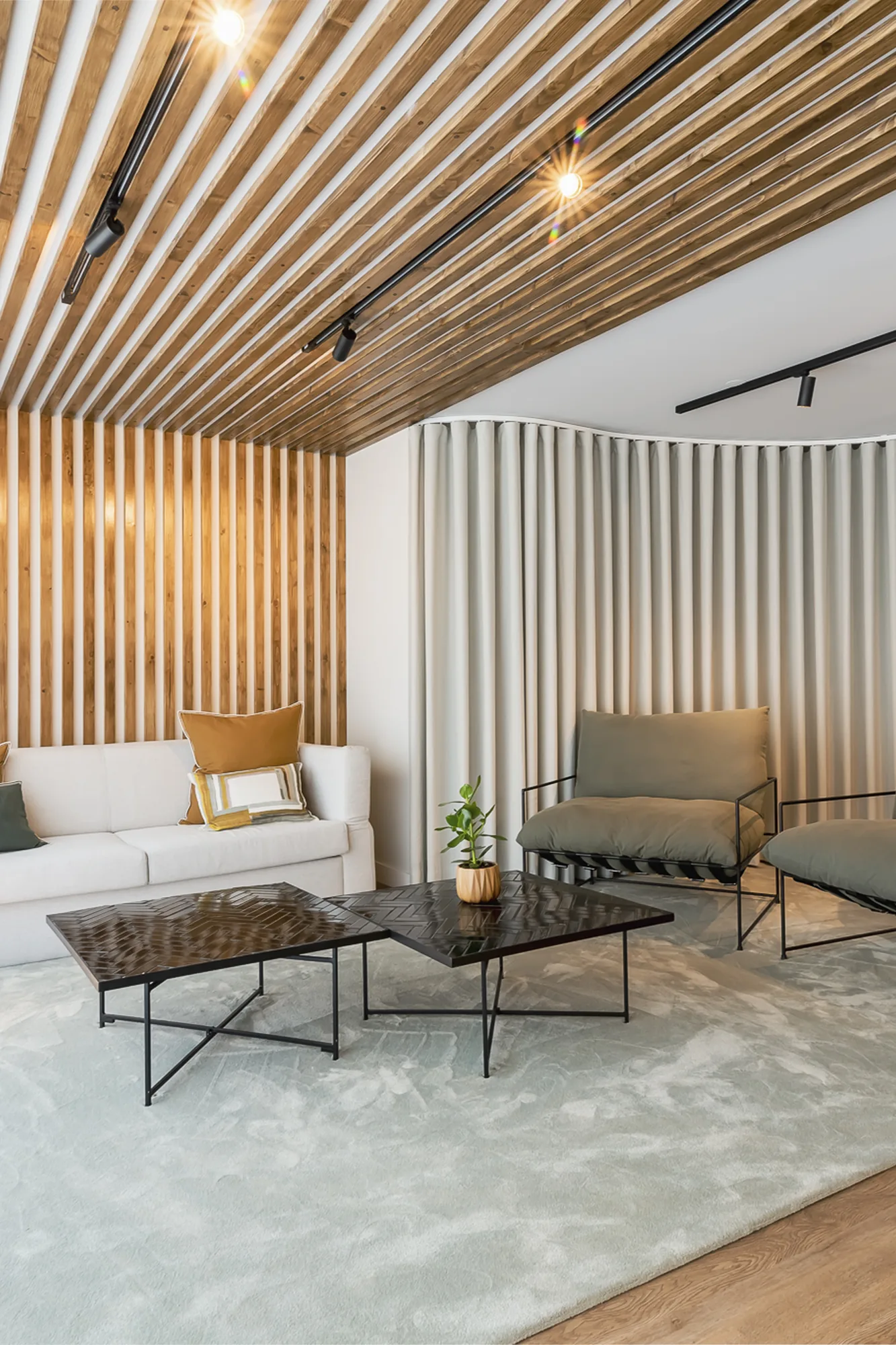 Zona de estar com tecto ripado em madeira, sofá claro e mesa de centro em pedra.