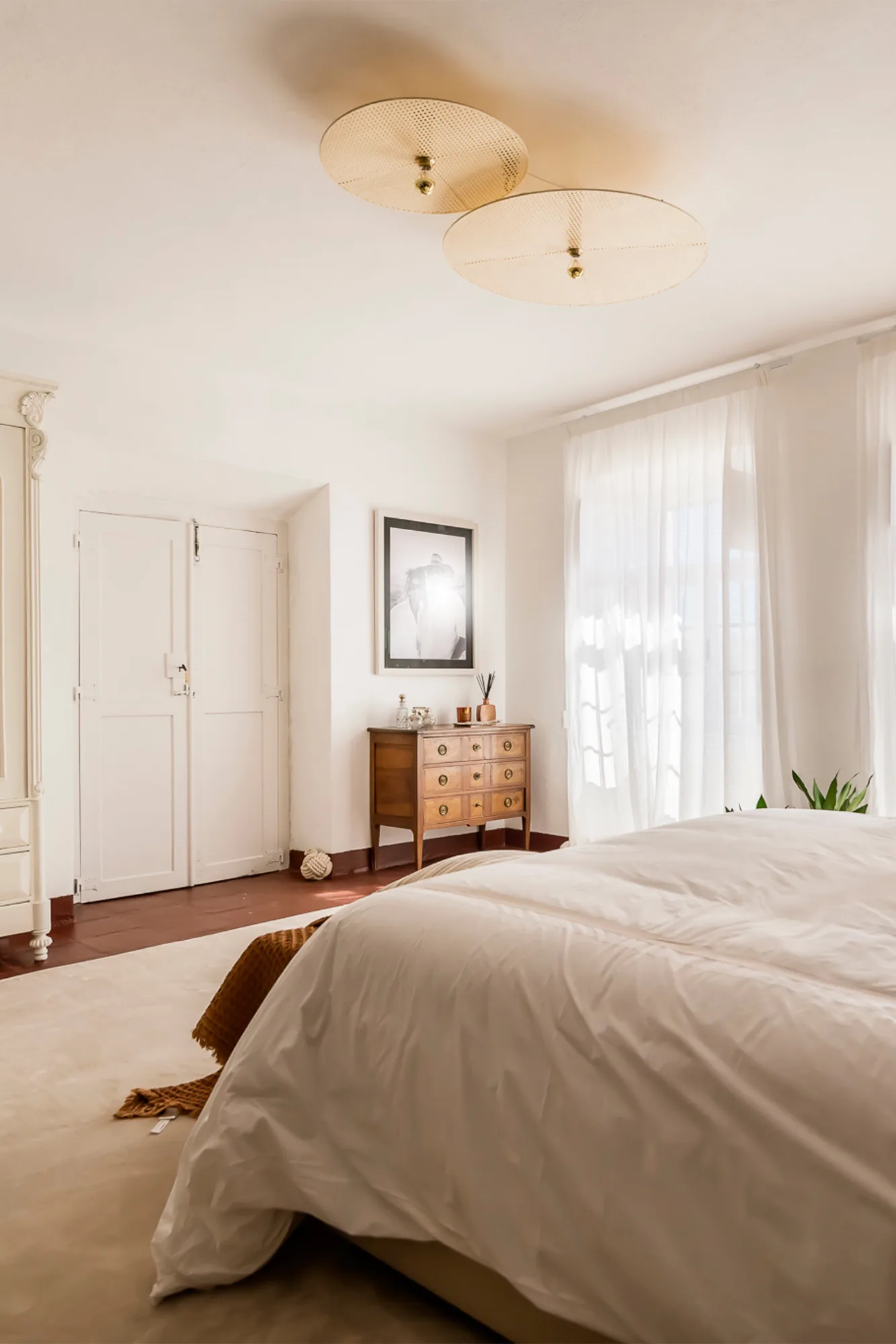 Quarto em branco com cómoda antiga, plafond de tecido e portadas de madeira.