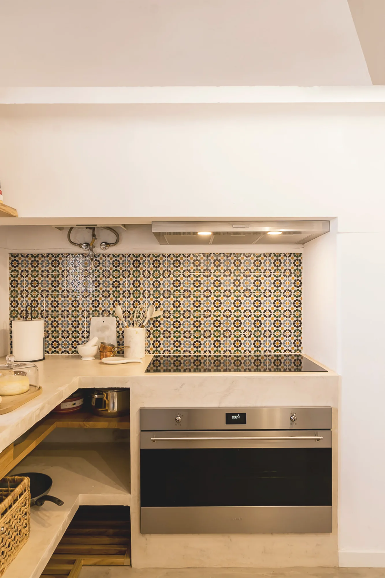 Zona de trabalho da cozinha com painel de azulejo padronizado e forno encastrado.